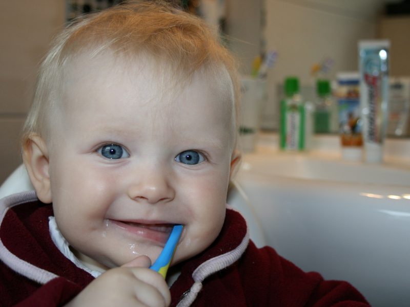 two year old boy in the bathroom smiling with a toothbrush in his hand
